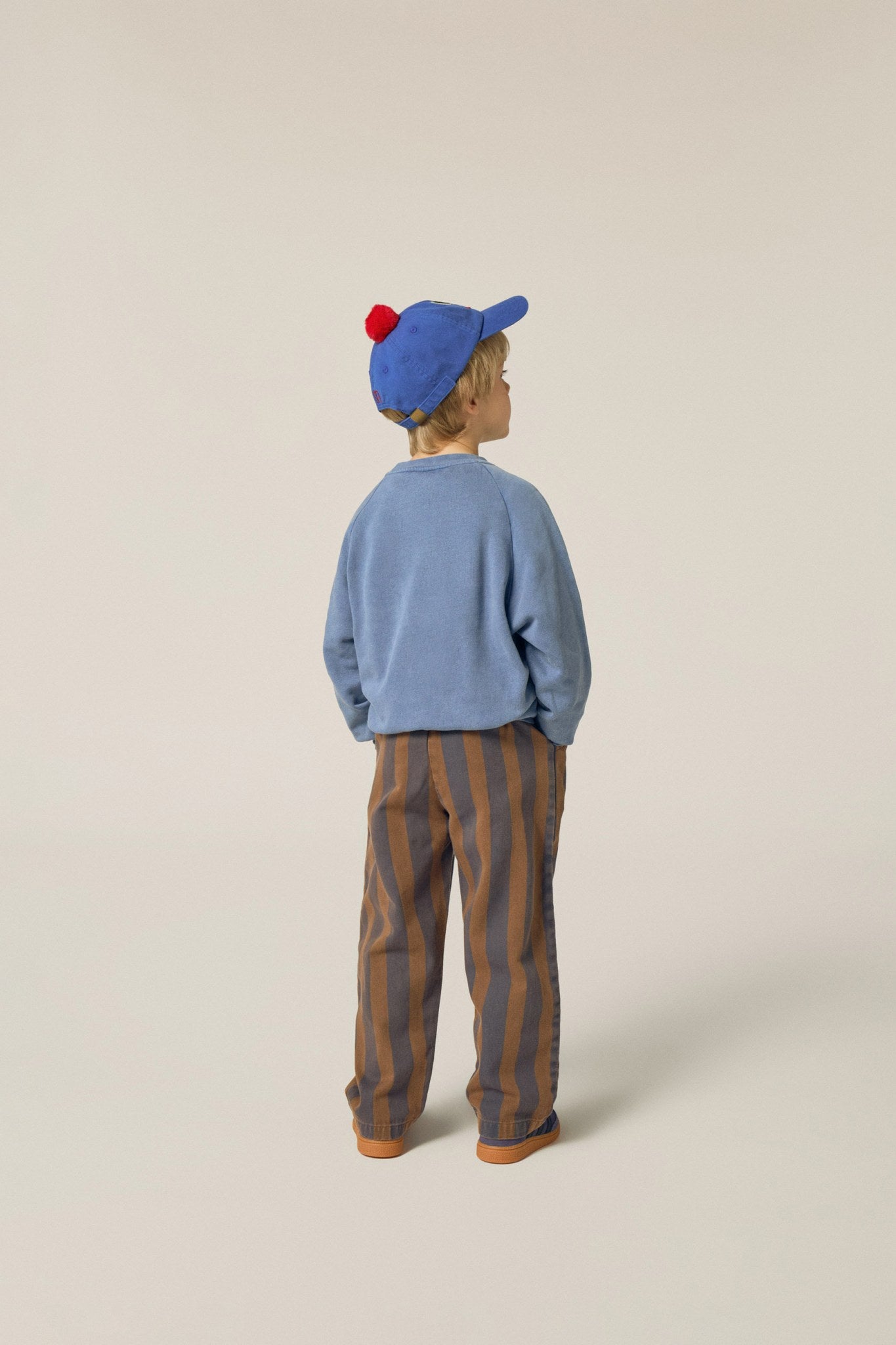 Niño de espaldas con pantalón de rayas verticales.