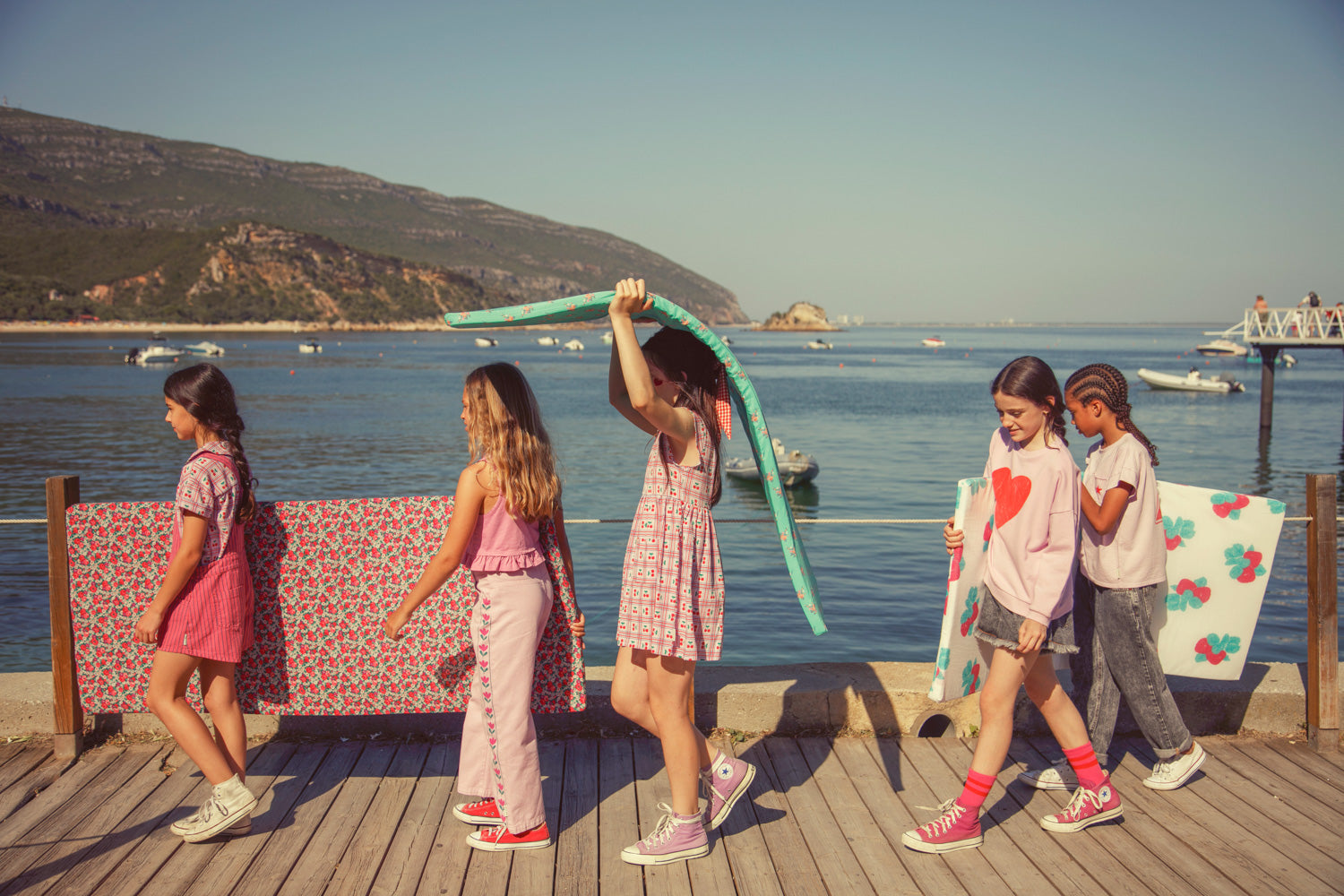 5 niños vestidos con la temporada de verano 2026 de Pipiuchick caminando por una tarima flotante en un puerto con el mar de fondo