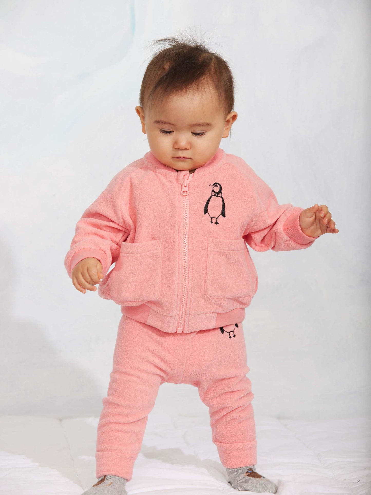 Modelo llevando chaqueta de niño rosa pingüino bordado de Mini Rodini.