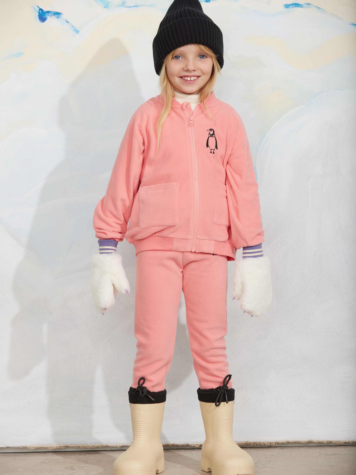 Modelo llevando chaqueta de niño rosa pingüino bordado de Mini Rodini.