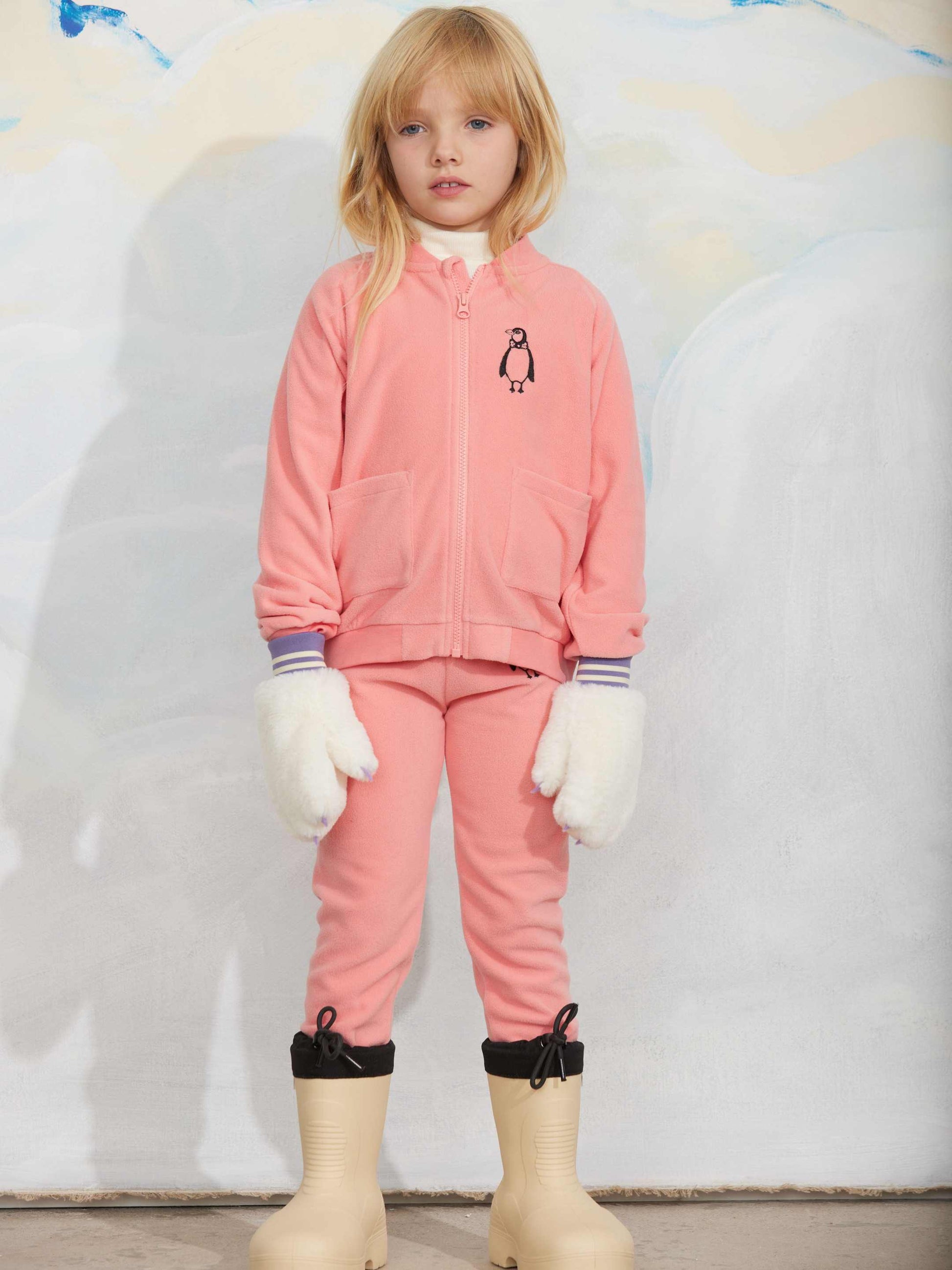 Modelo llevando chaqueta de niño rosa pingüino bordado de Mini Rodini.