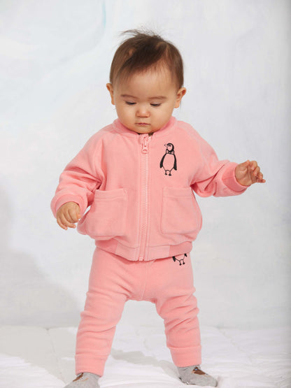 Modelo llevando pantalón de niño rosa pingüino bordado de Mini Rodini.