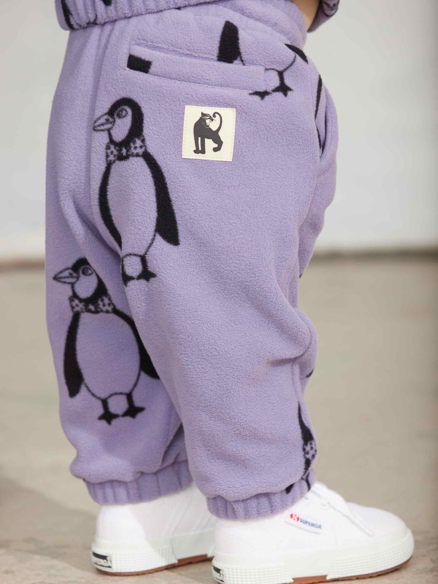 Modelo llevando pantalón de niño púrpura pingüinos de Mini Rodini.
