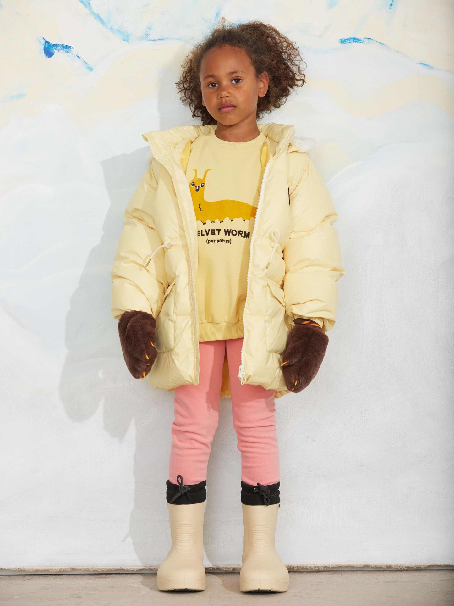 Modelo llevando sudadera de niño amarillo gusano velvet de Mini Rodini.