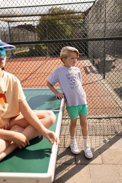 Niño con camiseta gris Cheetah Fun Club y pantalón corto verde.