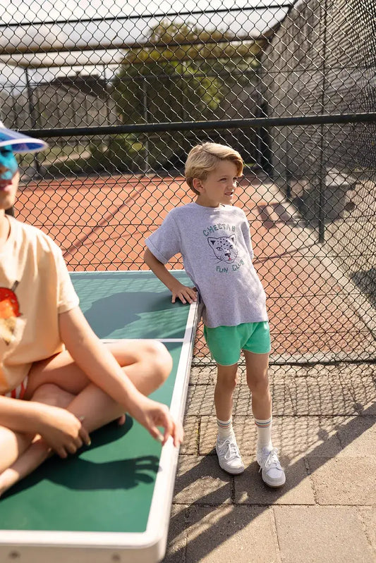 Niño con camiseta gris Cheetah Fun Club y pantalón corto verde.