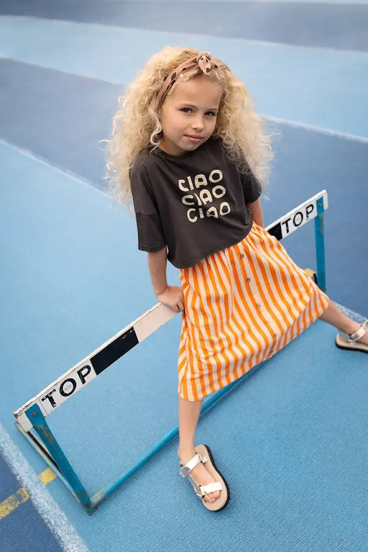 Niña con camiseta corta negra Ciao y falda de rayas de Sproet & Sprout.