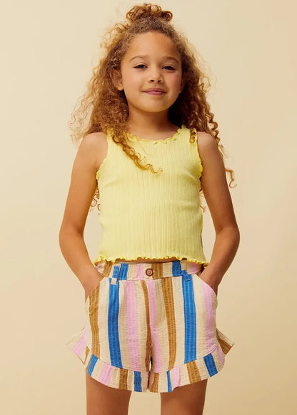Niña con camiseta amarilla de tirantes y pantalón de rayas de Sproet & Sprout.