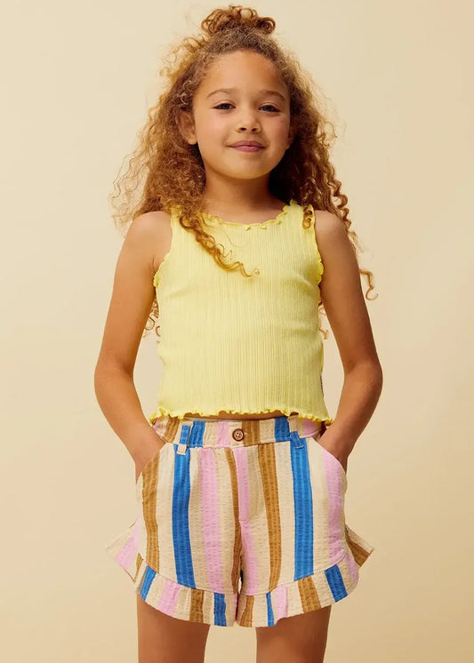 Niña con camiseta amarilla de tirantes y pantalón de rayas de Sproet & Sprout.