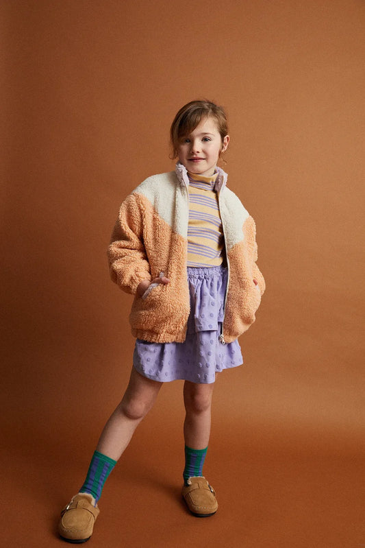 Persona posando con chaqueta de niña beige rosa Bloques de Color de Sproet & Sprout.