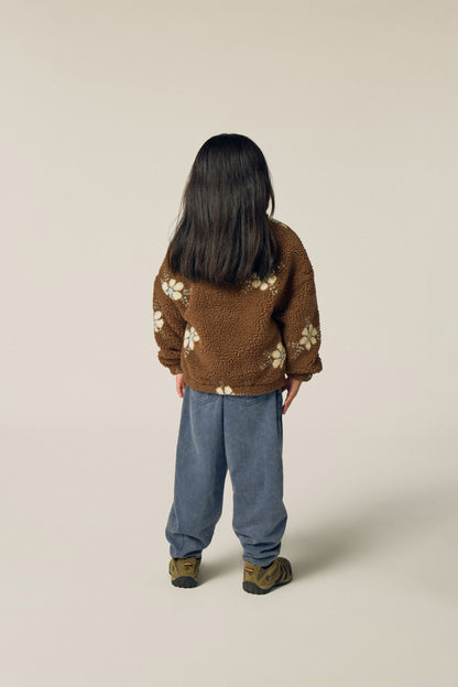 Niña de espaldas con la chaqueta marrón de flores.
