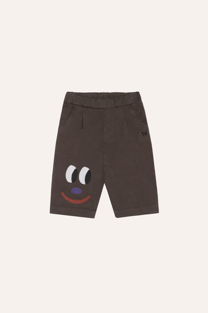 Pantalón corto de bebé marrón con cara sonriente, vista frontal.