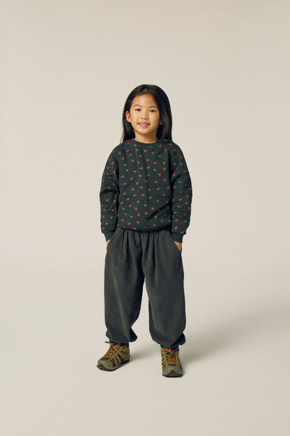 Niña posando de frente con pantalón gris oscuro de pana.
