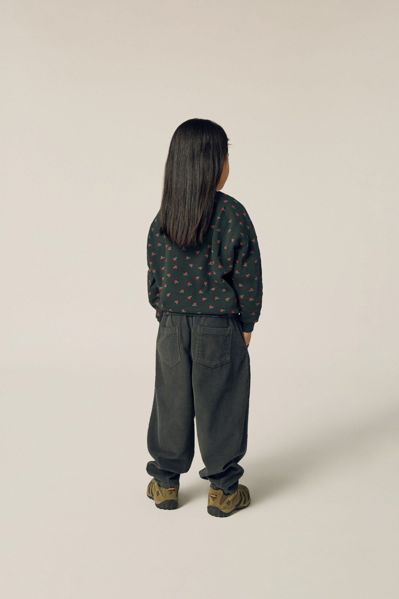 Niña de espaldas con pantalón gris oscuro de pana.