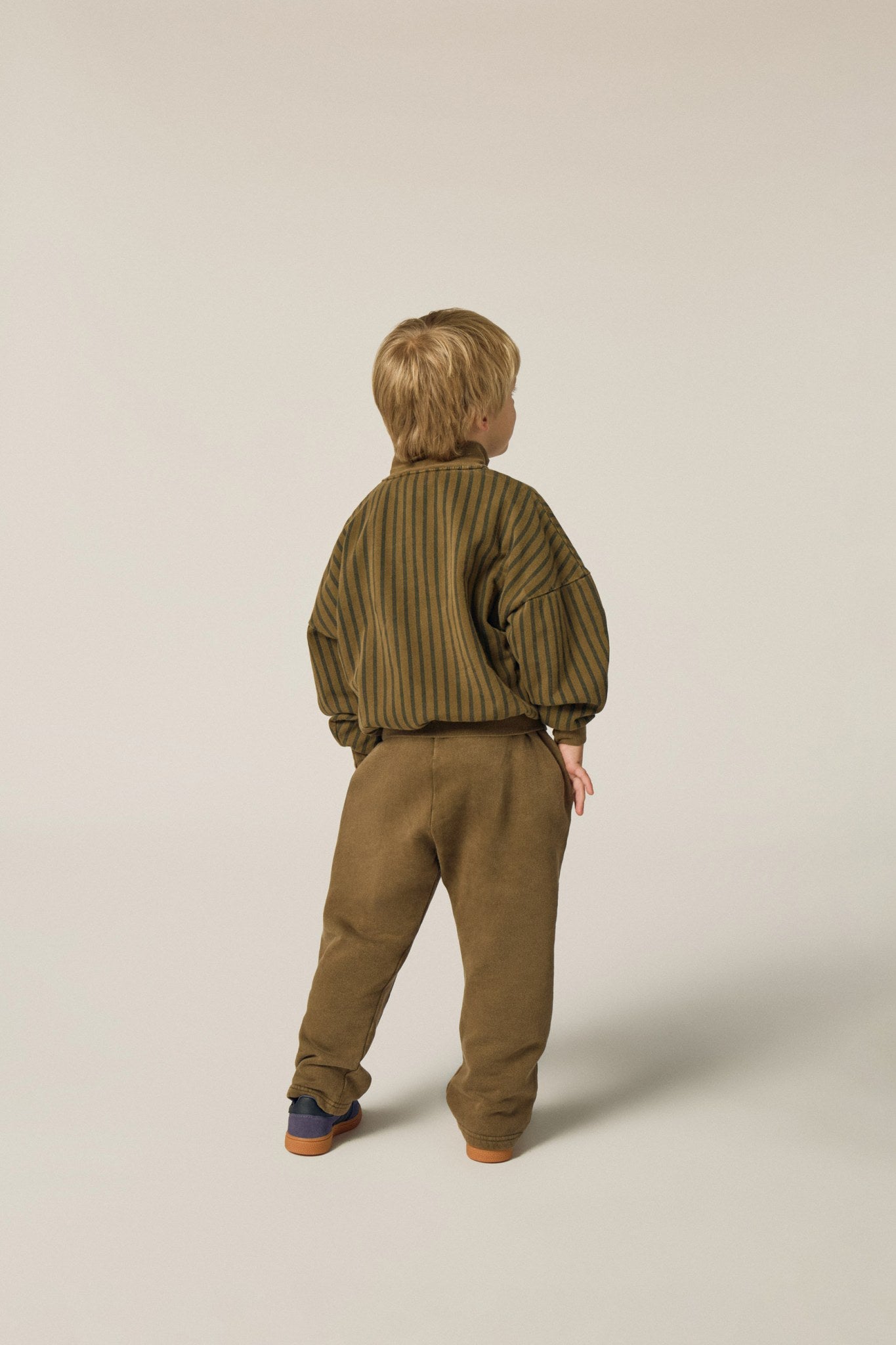 Niño de espaldas con pantalón marrón de corte holgado.