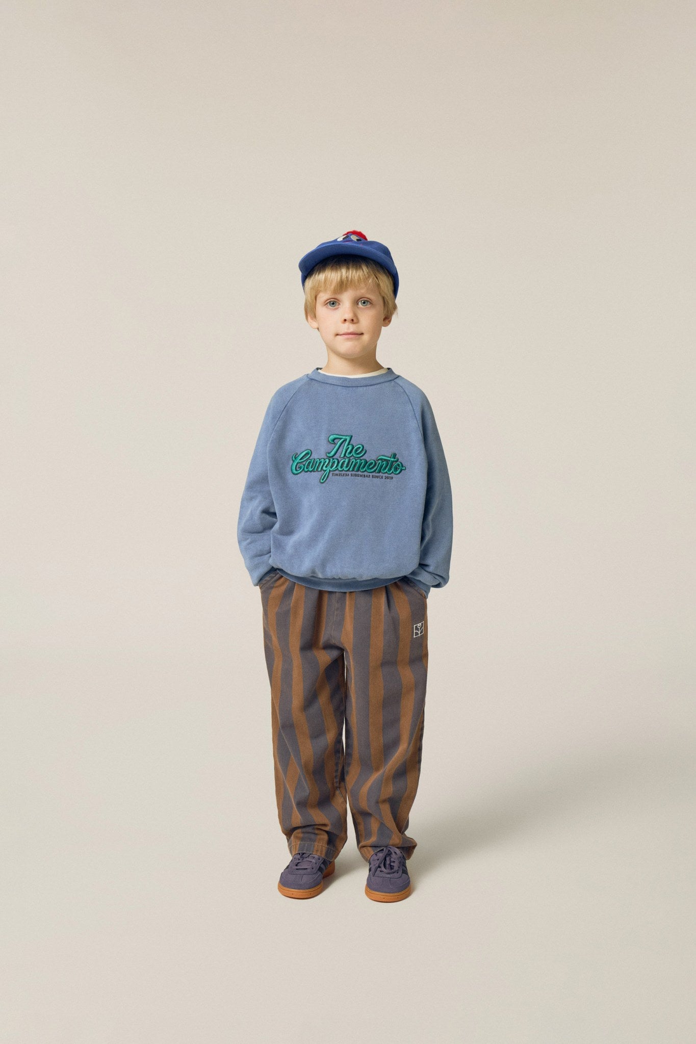 Niño posando de frente con pantalón de rayas verticales.