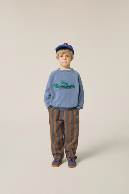 Niño posando de frente con pantalón de rayas verticales.