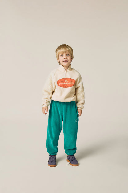 Niño posando de frente con pantalón verde de terciopelo.