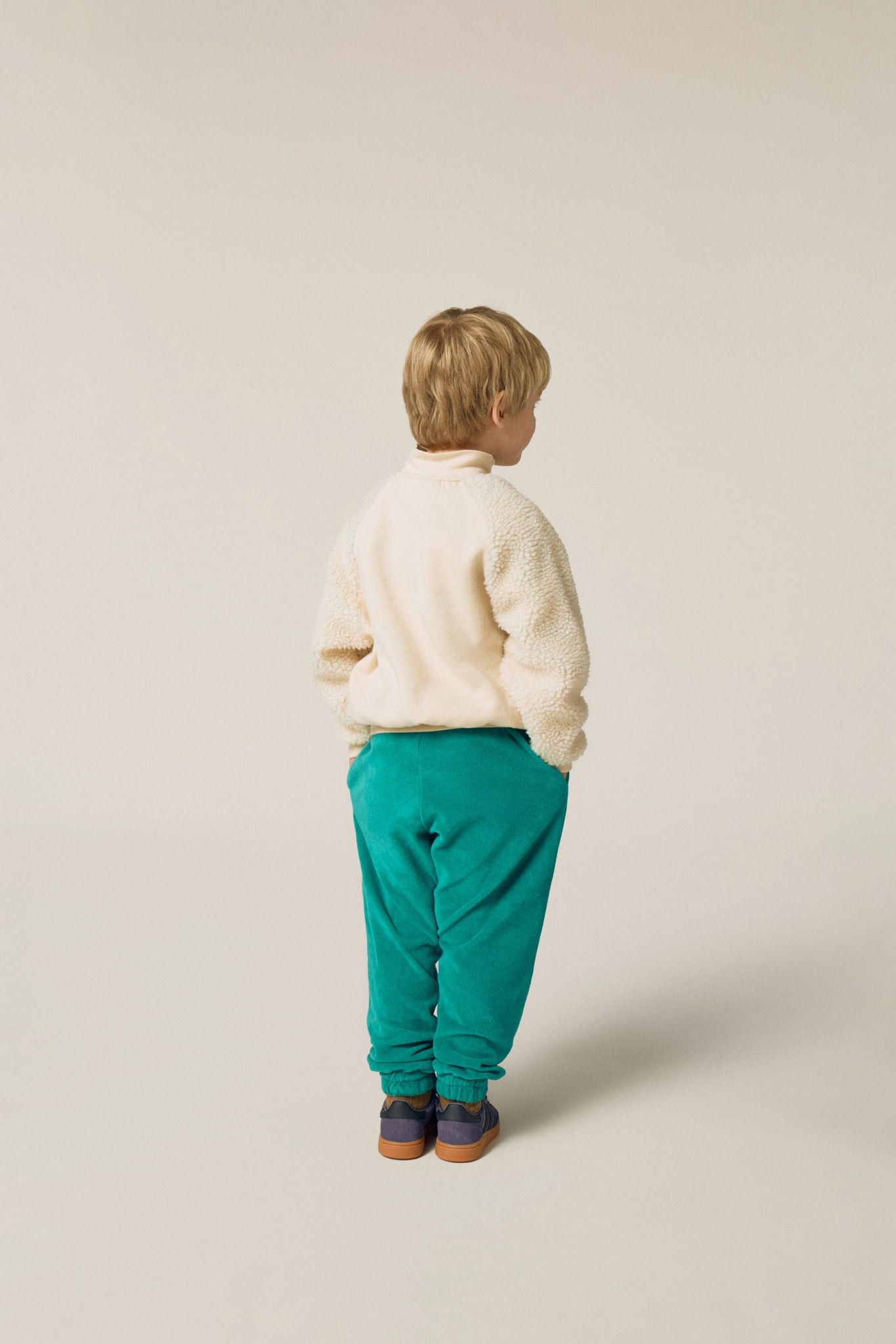 Niño de espaldas con pantalón verde de terciopelo.