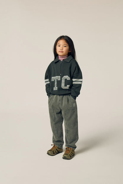 Niña posando de frente con la sudadera gris de letras TC.