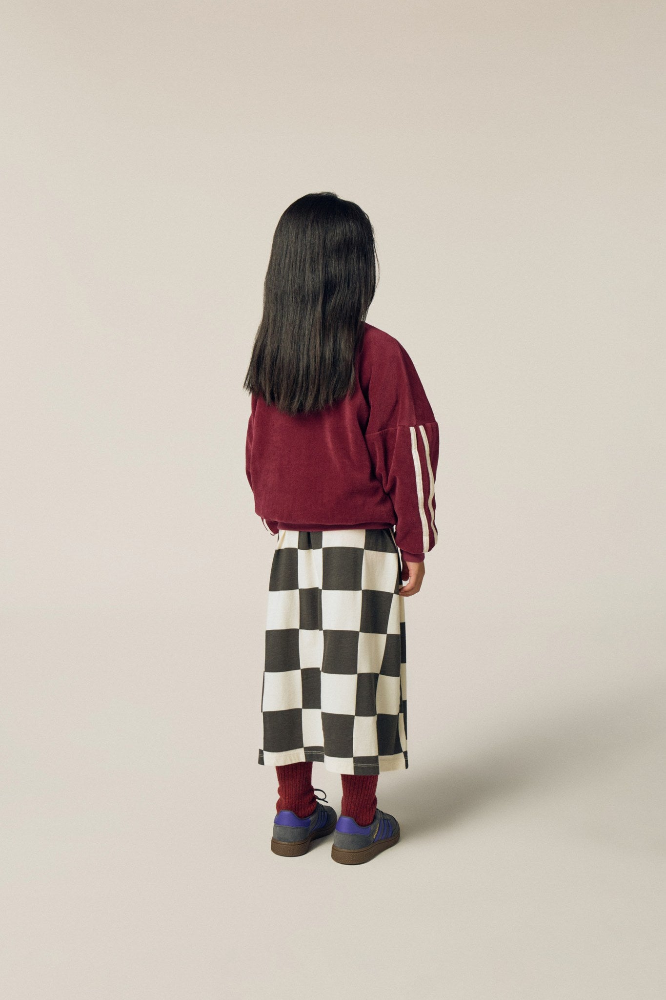 Niña de espaldas con la sudadera burdeos de terciopelo.