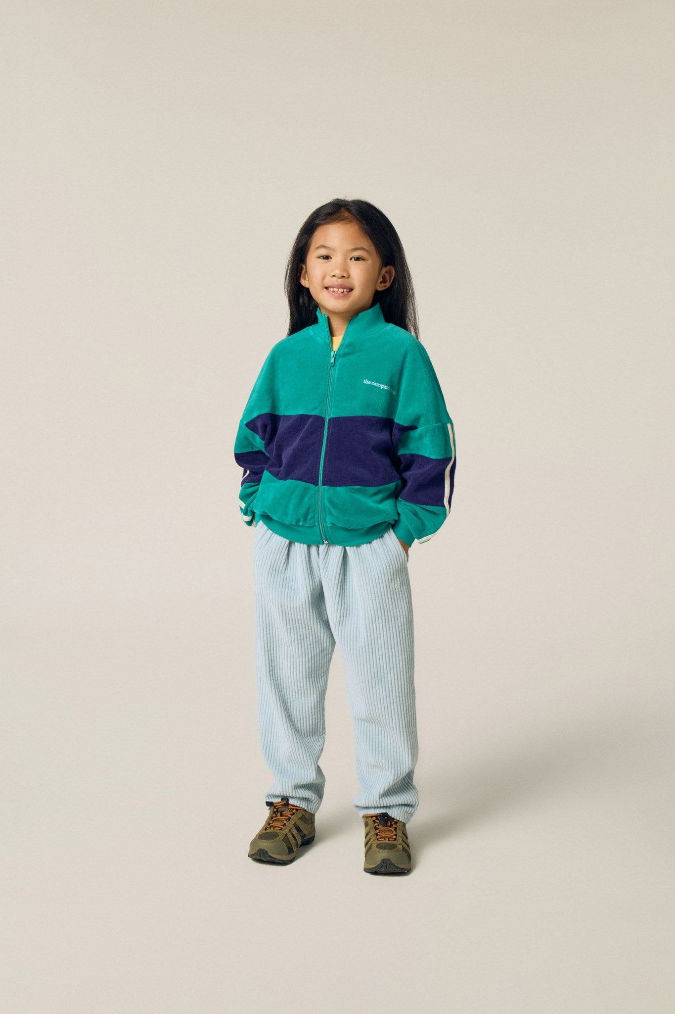 Niña posando de frente con la sudadera verde y azul.