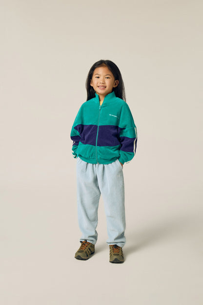 Niña posando de frente con la sudadera verde y azul.