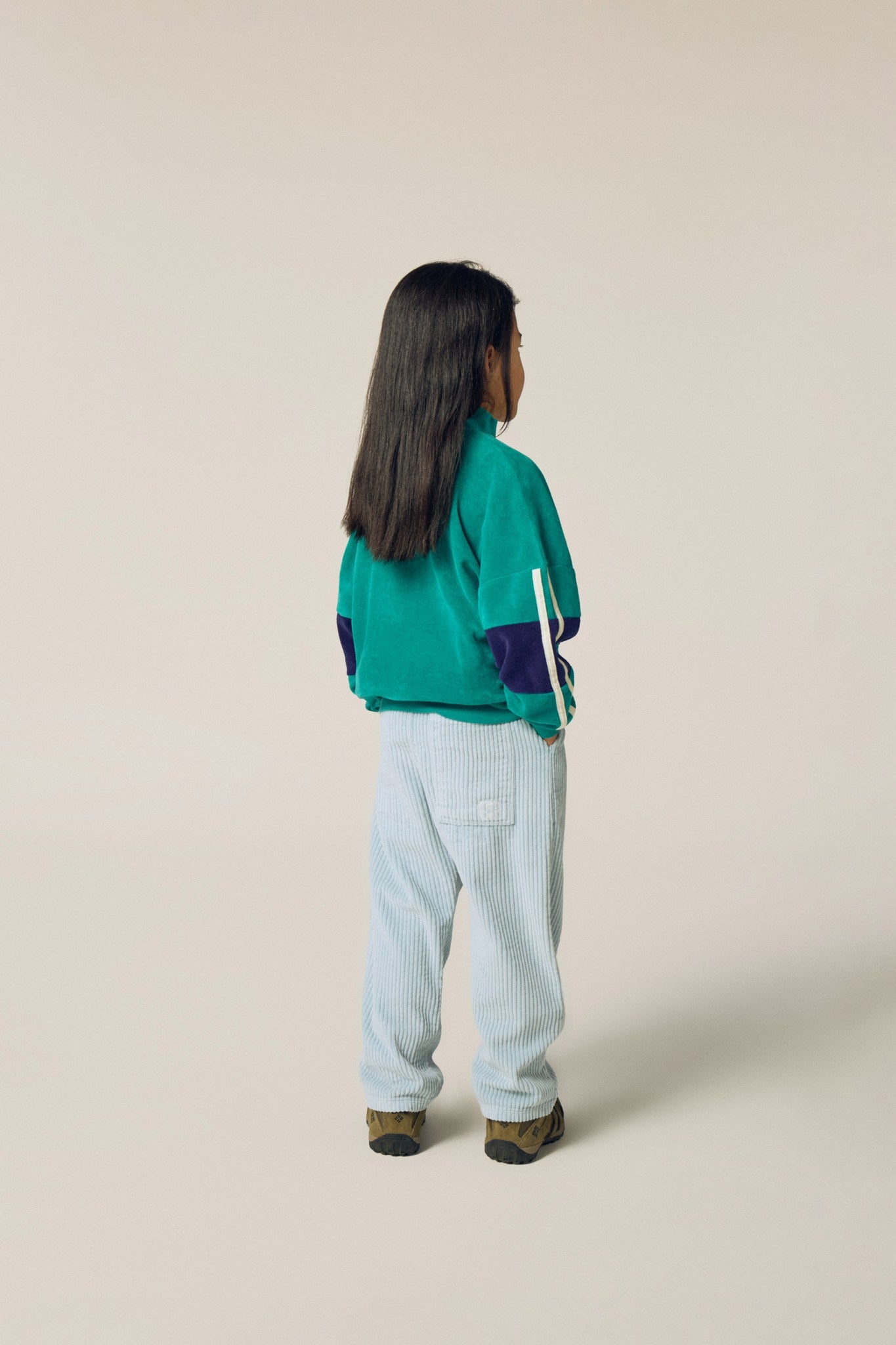 Niña de espaldas con la sudadera verde de terciopelo.