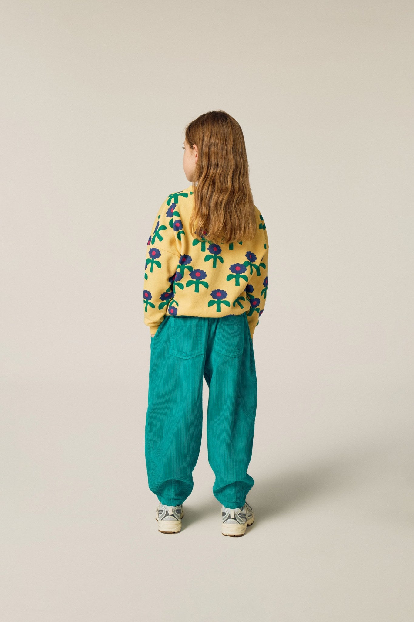 Niña de espaldas con la sudadera amarilla de margaritas.