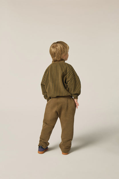 Niño de espaldas con sudadera y pantalón marrón.