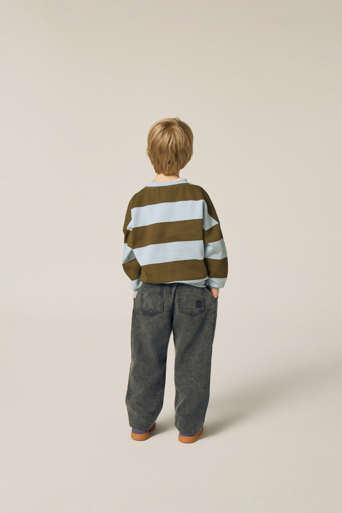 Niño de espaldas con la sudadera de rayas anchas.